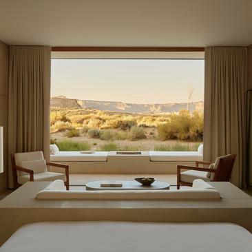 Desert pool suite bedroom at Amangiri resort overlooking golden landscape at sunrise.