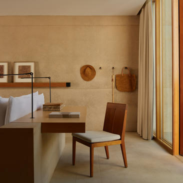 Mesa Suite bedroom at Amangiri resort, featuring warm earth tones, wooden furniture and natural light from floor-to-ceiling windows.