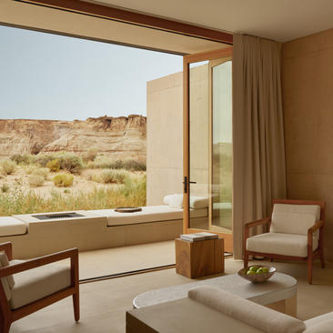 Orchard Suite at Amangiri with floor-to-ceiling windows framing desert landscape views and warm wood furnishings.