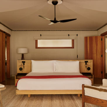Principal bedroom in a Camp Sarika pavilion at Amangiri, featuring a bed with red runner and wooden furnishings.