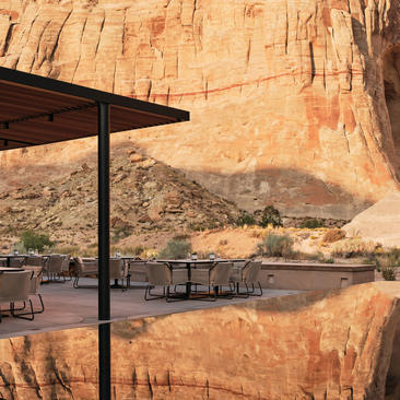 アマンギリ リゾートのキャンプ・サリカ・レストラン外のパティオ。砂岩の崖を背景に、シェード付きのテラス席が広がる。
