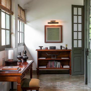 Pool suite study at Amantaka, with wooden desk, green-framed mirror and shelving unit.