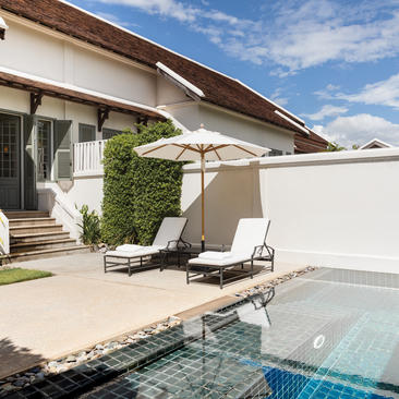 Amantaka villa with loungers beside a plunge pool, shaded by a canvas parasol.
