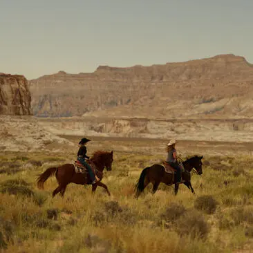 Riders on horseback across desert landscape at Amangiri resort, Utah.