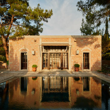 Amanruya pavilion with garden view, featuring terracotta-coloured architecture reflected in still water channel.