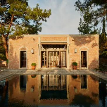 Amanruya pavilion with garden view, featuring terracotta-coloured architecture reflected in still water channel.