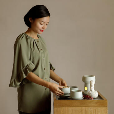 Woman preparing tea at Amanyangyun, China seasonal spa experience.