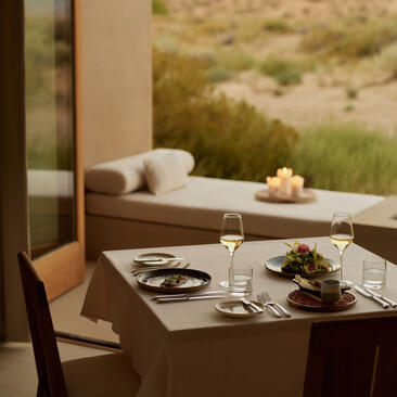 Dining area at Amangiri resort with plated dishes on table and desert landscape view beyond.