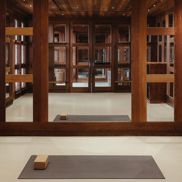 Yoga studio at Amangani with wooden-framed mirrors and a grey mat on pale flooring.