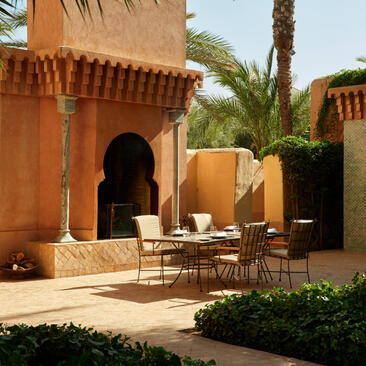 Maison Jardin suite terrace at Amanjena with ochre-rendered walls, palm trees and seating area.