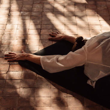 Personne en tenue de yoga allongée dans un pavillon à Amanjena, resort au Maroc.