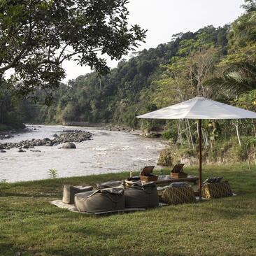 Riverside picnic area at Amanjiwo with shaded seating overlooking the Progo River in Central Java, Indonesia.
