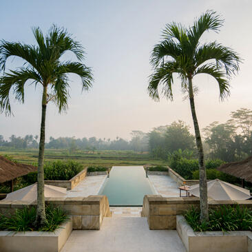 Dalem Jiwo Suite view at Amanjiwo with plunge pool overlooking misty Indonesian landscape and palm trees.