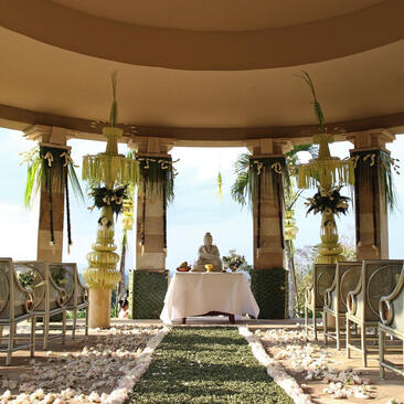 Wedding ceremony setup at Amanjiwo with altar beneath domed pavilion, flanked by floral arrangements and columns.