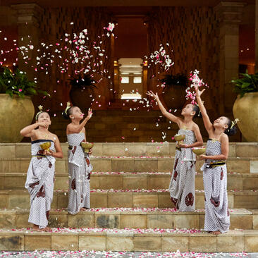 Celebration gathering at Amanjiwo with guests in traditional Javanese dress on stone steps adorned with festive lights and greenery.