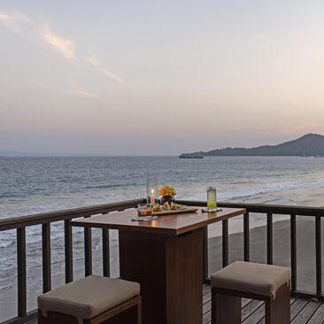 Table set for two on a seaside terrace at Amankila resort, Bali, at dusk.