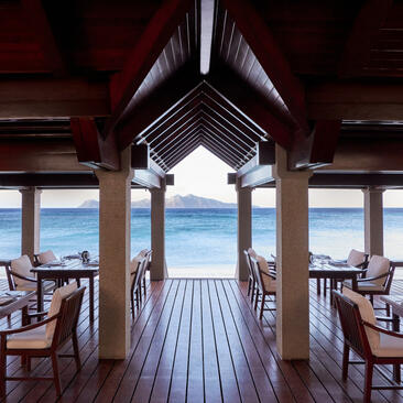 Beach club pavilion at Amanpulo with wooden deck and sea views through open columns.