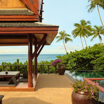 Wooden pavilion with ocean views at Amanpuri, framed by palm trees and tropical landscape.