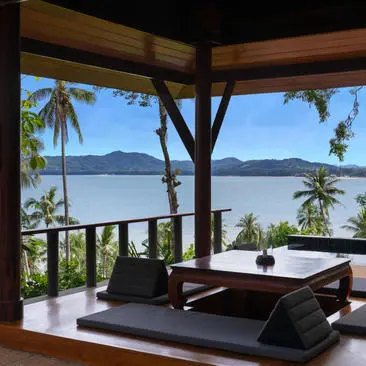 Pool pavilion at Amanpuri overlooking the bay, with wooden beams and open-air seating.