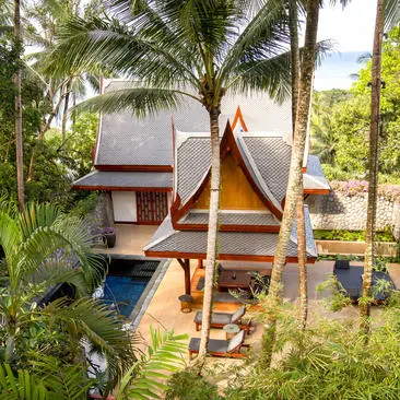 Garden pool pavilion at Amanpuri Thailand, with teak structure nestled among palm trees and tropical foliage.
