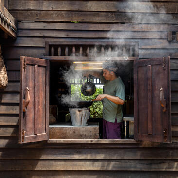 Wooden shutters open onto a serene altar space at Amansara, with incense smoke and fresh flowers visible within.