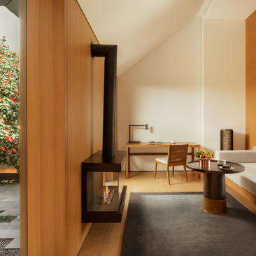 Ming Pavilion bedroom at Amanyangyun with wood panelling, central fireplace, and contemporary furnishings.