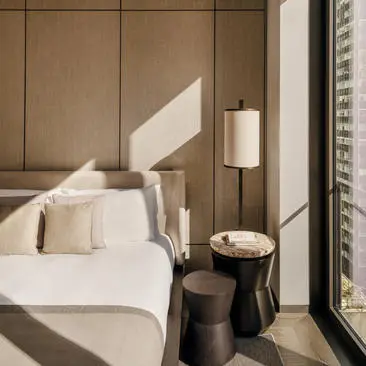 Two-bedroom home at Aman New York with a principal bedroom featuring a bed with white linens and warm wood paneling.