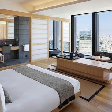 Grand Suite king bedroom at Aman Tokyo with floor-to-ceiling windows overlooking the city skyline.
