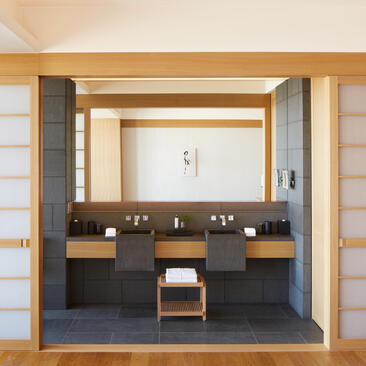 Twin suite bathroom at Aman Tokyo with dual vanities, dark cabinetry, and minimalist design.