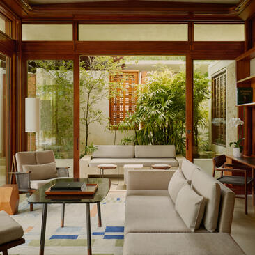Amanera living room with cream seating, wooden frames, and garden views through large windows.