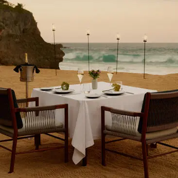Beachfront dining setup at Amanera resort in the Dominican Republic, with two chairs facing the ocean waves.