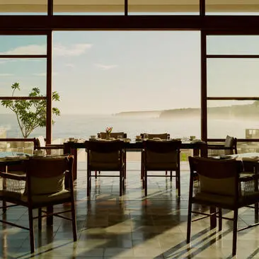Comedor principal de Amanera con mesas de madera, sillas y vistas panorámicas al paisaje dominicano.