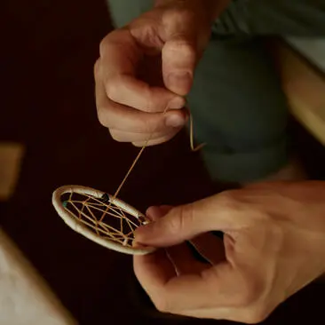 Hands crafting a dreamcatcher during a workshop at Amangiri resort.