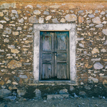 Weathered stone wall with blue-green wooden door at Amanruya, Turkey.