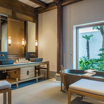 Four-bedroom villa bathroom at Amanyangyun featuring wooden vanity, large mirror and soaking tub overlooking gardens.