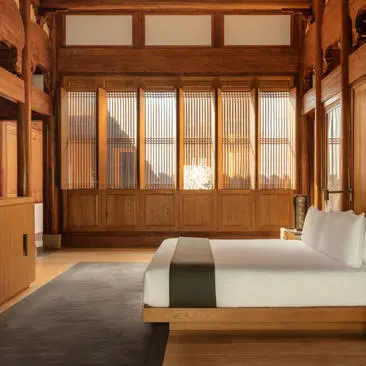 Minimalist villa bedroom at Amanyangyun with wooden architectural details and floor-to-ceiling windows overlooking gardens.