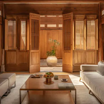 Amanyangyun villa lounge with wooden cabinetry, low table and cream seating.