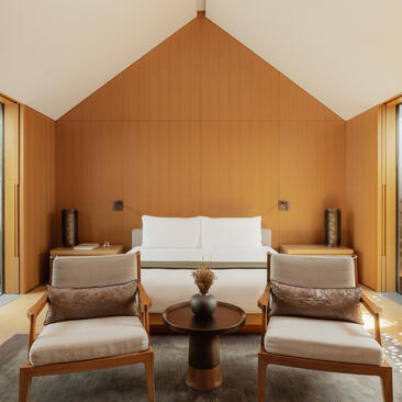 Ming Pavilion bedroom at Amanyangyun with ochre-toned walls, symmetrical seating and central bed.