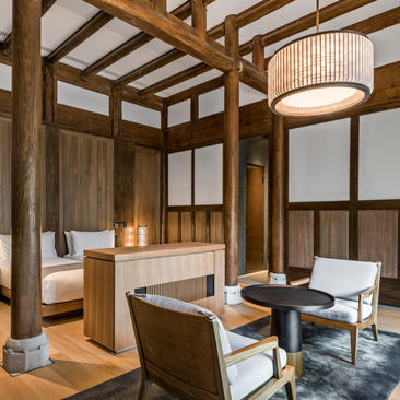 Guest bedroom at Amanyangyun with four-poster bed, wooden beams, and sitting area by windows.