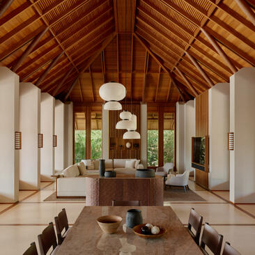 アマンヤラのヴィラ内部。木製の高い天井、白い壁、中央に暖炉のある広々としたリビングエリア。