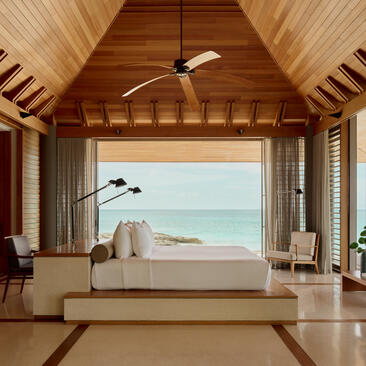 Spa villa bedroom at Amanyara with vaulted wooden ceiling, freestanding bath overlooking turquoise waters, Turks and Caicos.