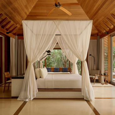 Amanyara pavilion with draped four-poster bed and views to tropical gardens through open doors.
