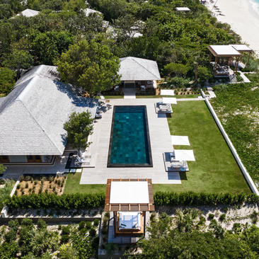 Aerial view of Amanyara's five-bedroom beach sala villa with rectangular pool, manicured gardens and white pavilions.