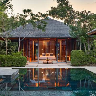 Four-bedroom beach villa at Amanyara with wooden architecture reflected in infinity pool at dusk, Turks and Caicos.