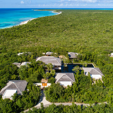 Four-bedroom beach villa at Amanyara surrounded by tropical vegetation with turquoise waters beyond.