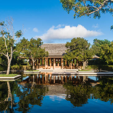 Six-bedroom beach sala villa at Amanyara overlooking a calm lagoon, surrounded by tropical vegetation and clear skies.