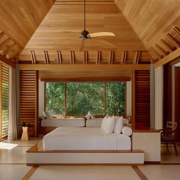 Principal bedroom in a three-bedroom villa at Amanyara, with wooden ceiling, louvred walls and views to tropical greenery.