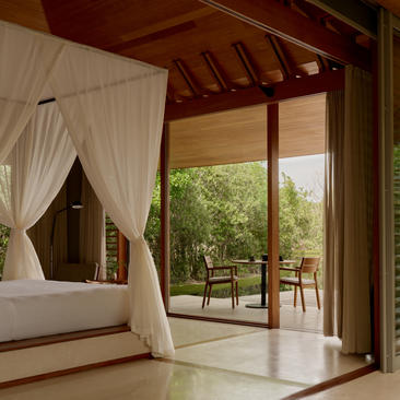 Principal bedroom with four-poster bed and sheer drapes opening to tranquility pavilion terrace at Amanyara, Turks and Caicos.