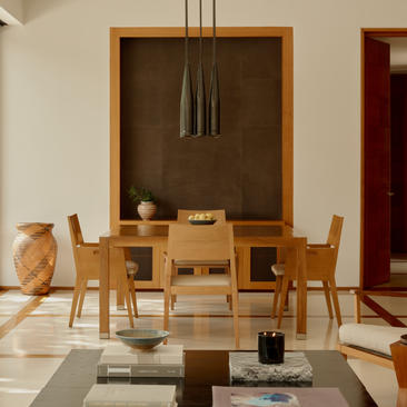 Two-bedroom pool villa dining area at Amanyara, Turks and Caicos, with wooden table and chairs beneath a wall-mounted art installation.