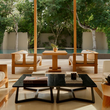 Two-bedroom pool villa at Amanyara with wooden chairs and black coffee table on terrace overlooking tropical gardens.